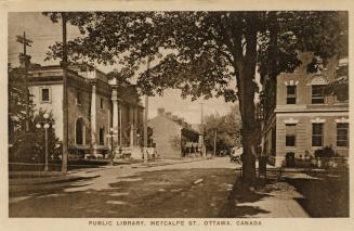 Street scene showing wide treed street with library building on left and other building on righ ...