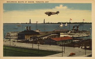Colorized photograph of steam boats moored in front of busy docks. Plane is flying overhead.