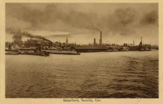 Black and white photograph of steamships and boats moored a docks beside a large city.