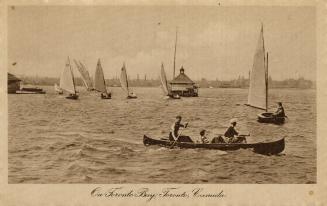 Black and white photograph of three people in a canoe and sailboats on choppy water.