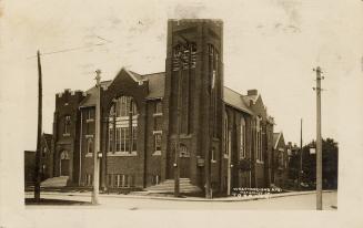Black and white photograph of a large church on a street corner.