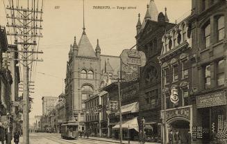 Black and white photograph of large buildings on a downtown street with a streetcar.