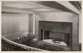 Black and white photograph of a person playing a piano on a stage in a theatre, taken from a lo ...