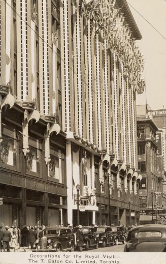 Black and white photograph of the front of a department store with banners and two lions rampan ...