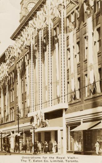 Black and white photograph of the front of a department store with a crest with the profiles of ...