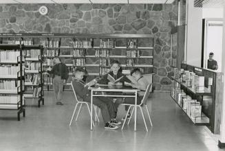 Picture of boys and girls looking at books in a library.
