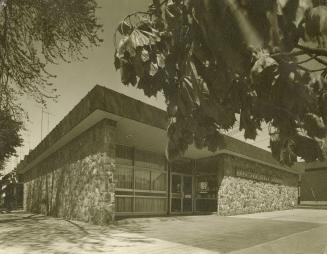 Picture of exterior of one storey library with stone facing. 
