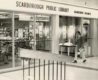 Picture of man walking past library branch inside a mall. 