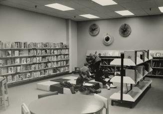 Picture of interior of library branch and people reading books. 