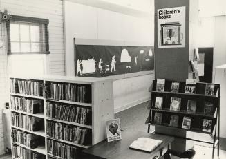 Picture of interior of library branch showing bookshelves in children's area. 