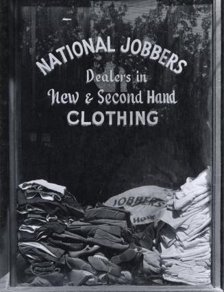 A photograph of a store window, with the words "NATIONAL JOBBERS / Dealers in / New & Second Ha ...