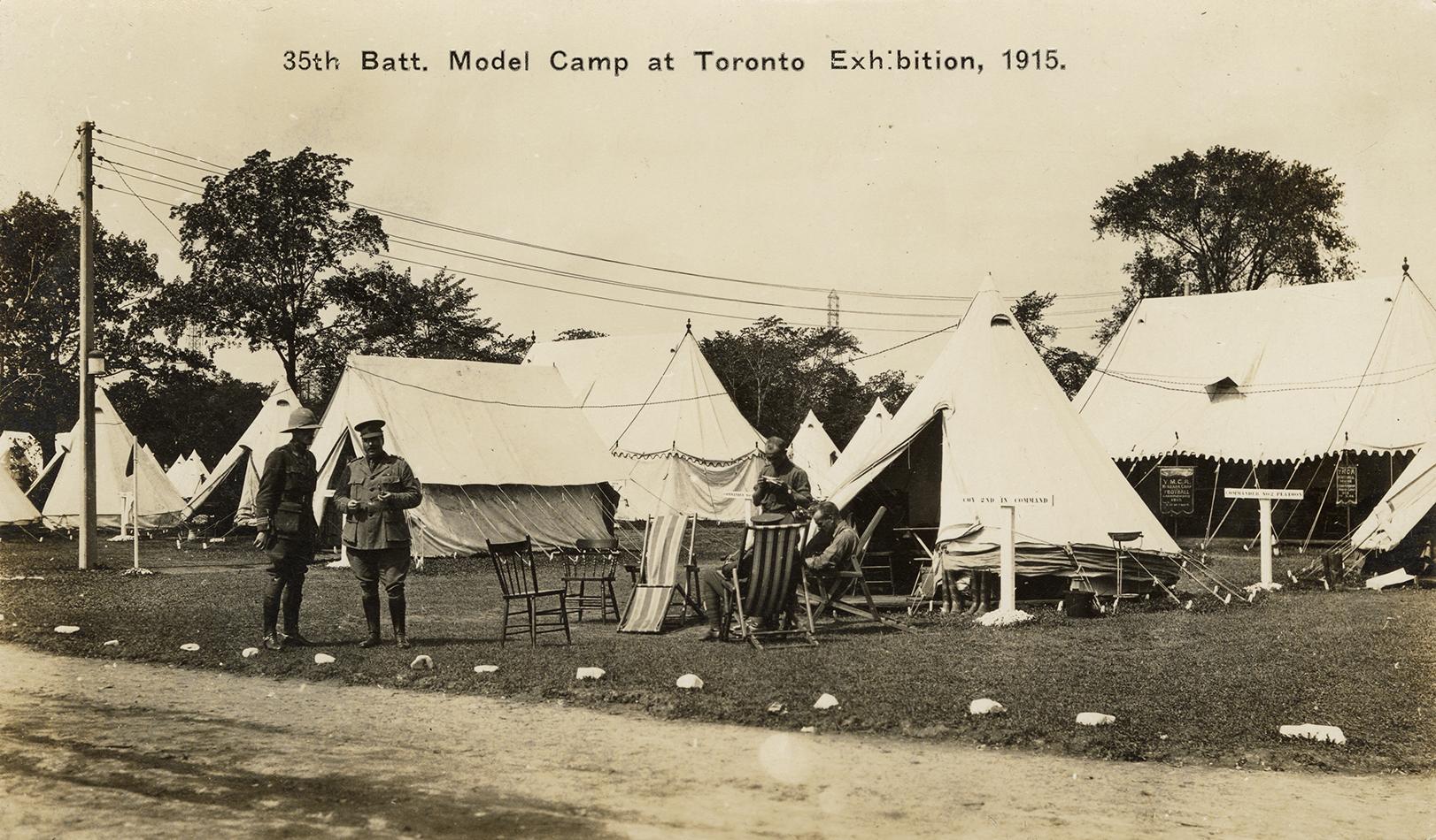 Black and white picture of soldiers standing in front of tents.