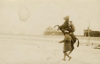 Black and white pictures of a soldier riding a rearing horse while another soldier looks on.
