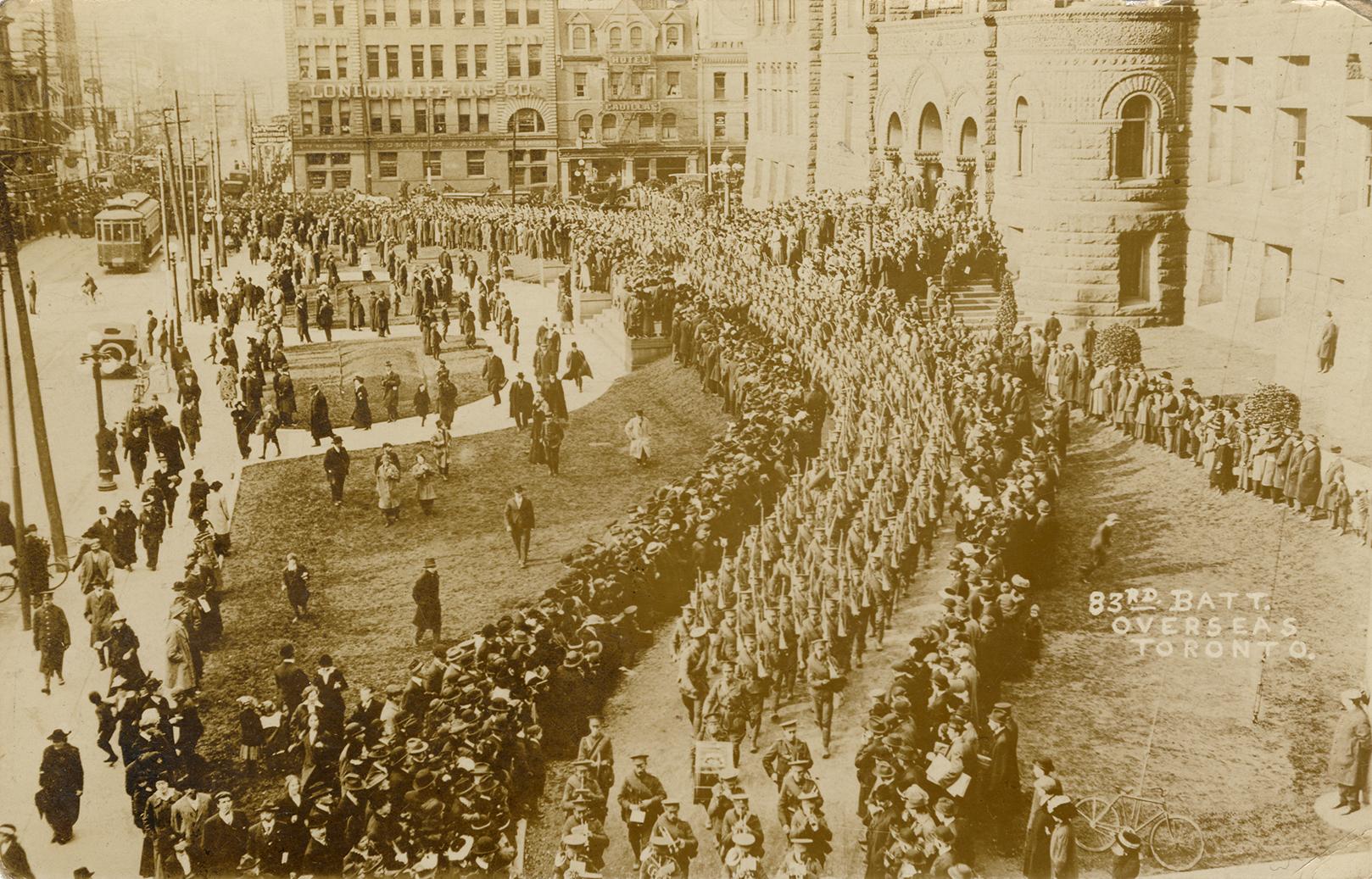 Black and white picture of soldiers marching in front of large, Richardsonian Romanesque buildi ...