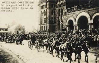 Black and white picture of soldiers riding in horse drawn carriages in front of dignitaries sta ...