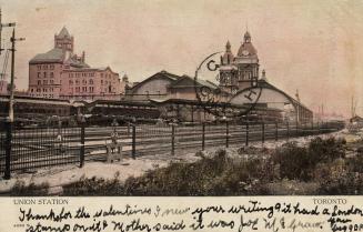 Colour photo postcard depicting a ground view of the tracks and exterior of Union station. The  ...