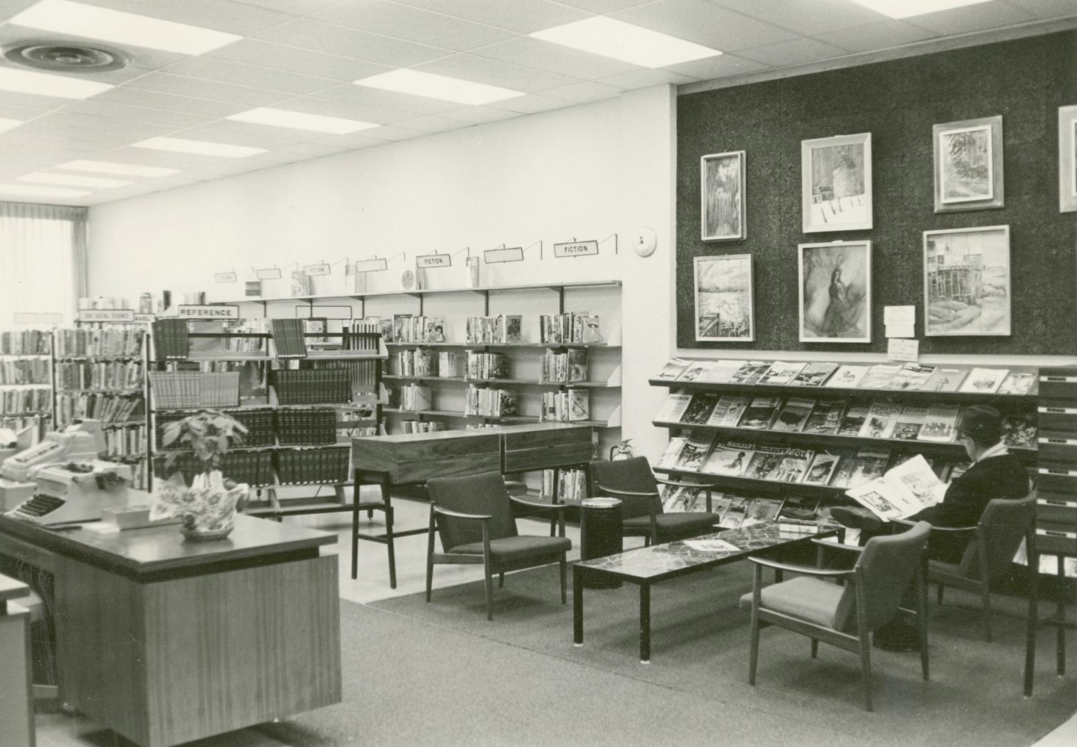 Picture of the interior of a library showing shelving and seating area with magazines. 