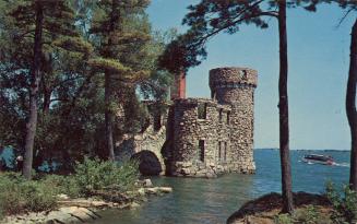 Color photograph of a large, stone castle on a riverbank