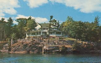 Colorized photograph of an island with a big house built on it in the middle of a river.
