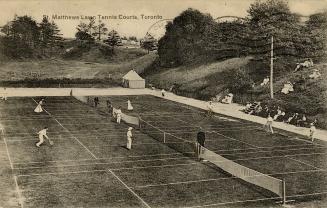 Black and white photo postcard depicting lawn tennis with several individuals playing on the co ...