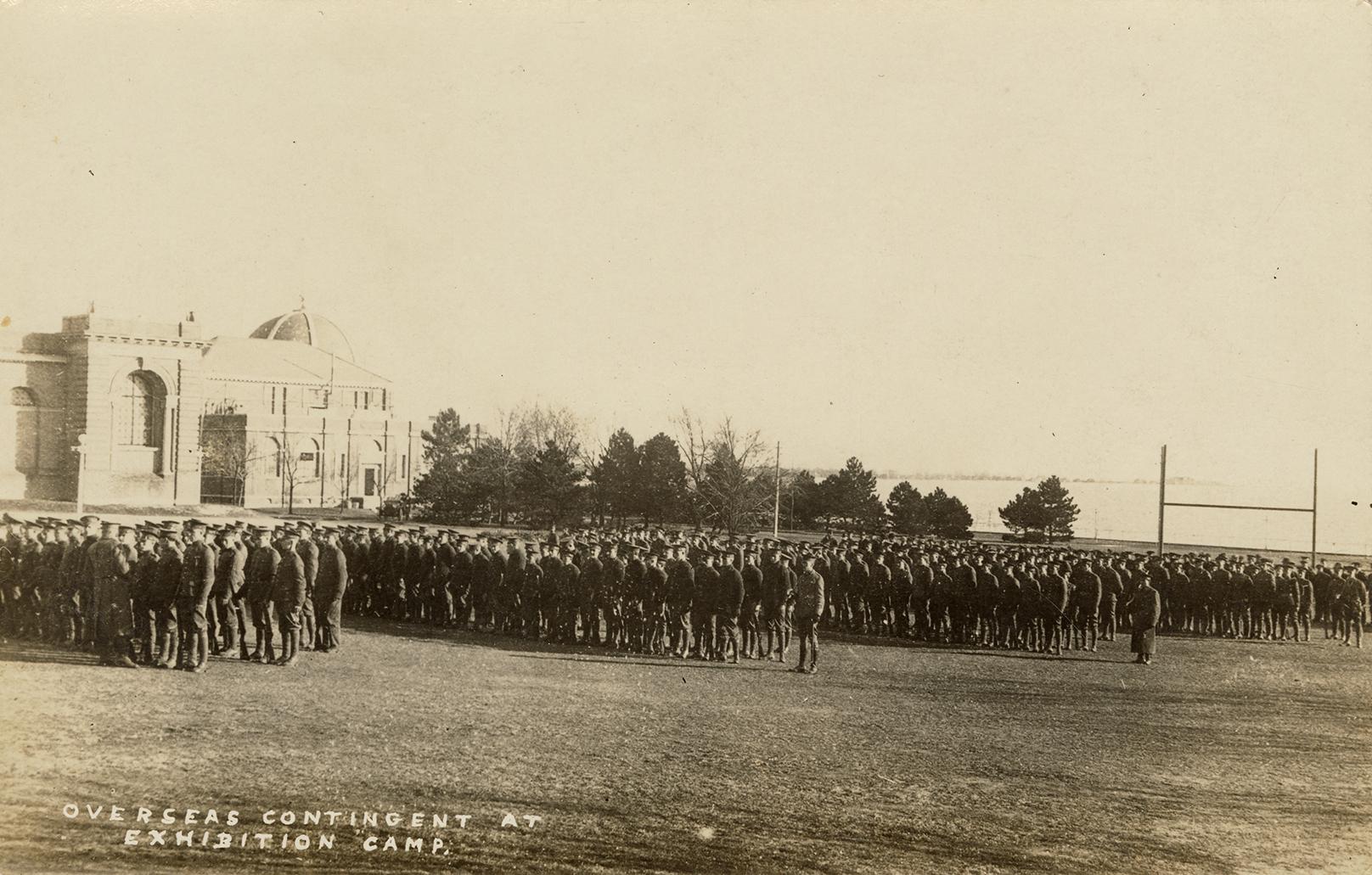 Black and white photograph of lines of servicemen in front of very large buildings.