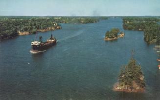 Color photograph of a large ship on a large river with islands in it.