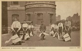Sepia toned photograph of men in civilian clothes holding semaphore flags standing in front of …