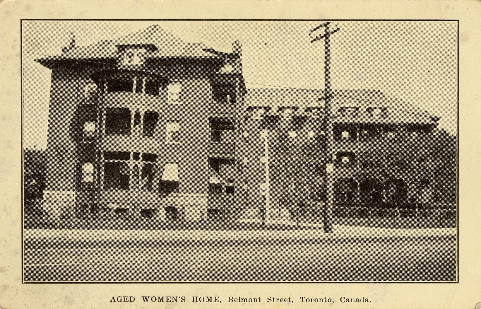 Black and white photograph of a four story public building. Circular and rectangular balconies.
