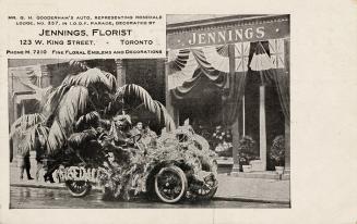 Black and white photograph of an automobile covered in flowers in front of the plate glass wind ...