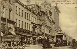 Sepia-toned photo postcard depicting a view of Yonge Street with many shops, a streetcar, and p…