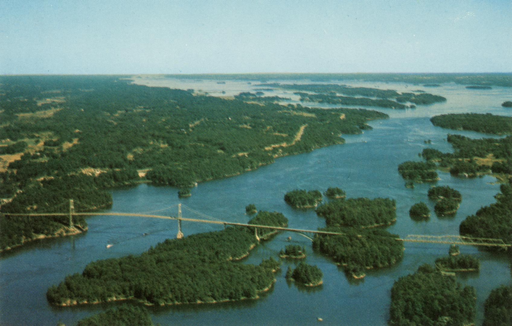 Colorized aerial photograph of a bridge spanning a river over many islands.