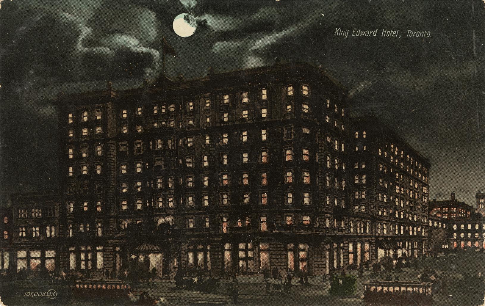 Color photograph of a large, multi story public building taken at night time. Full moon.