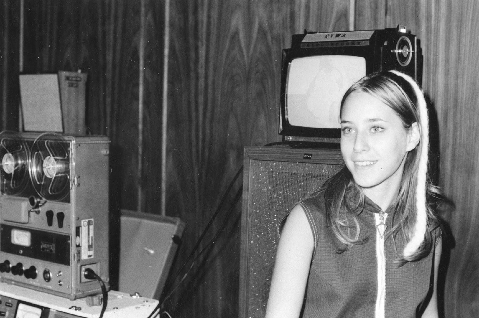Picture of a girl beside recording equipment.