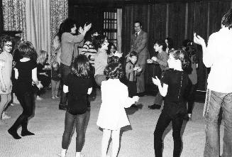 A group of children in a circle clapping and dancing to music. 