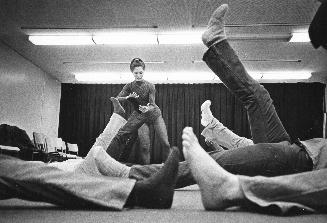 Picture of raised legs and instructor in an exercise class. 