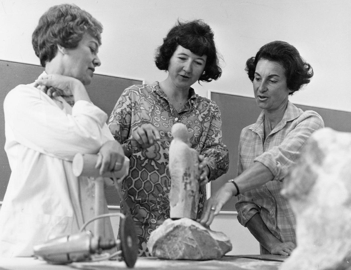 Picture of three women examining a sculpture. 