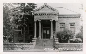 Picture of one storey stone library building with pillars at entrance.