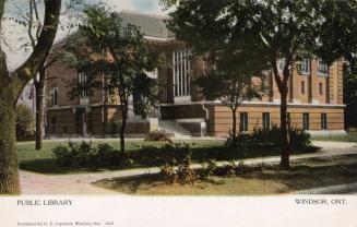 Picture of large brick library building with trees in front. 