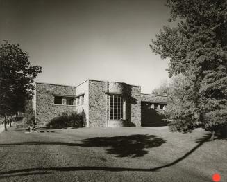 Picture of one side of a library building and lawn and tree. 