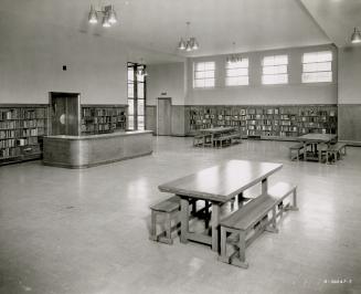 Picture of alcove in a library with shelving around the walls and one table in the middle. 