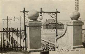 Black and white photograph of a large building on the other side of a stone gate.