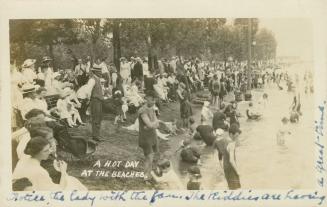 Black and white photograph of a huge crowd of people sitting on a shoreline.