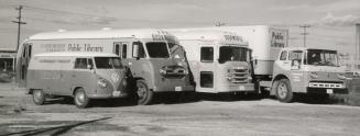 Picture of four bookmobiles in a parking lot arranged from the smallest (VW van) to largest tru ...