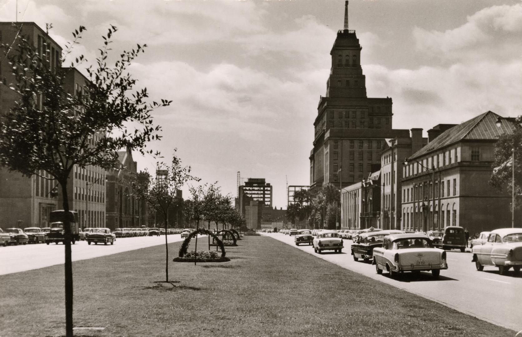 Black and photograph of a wide, city street with four lanes of cars.