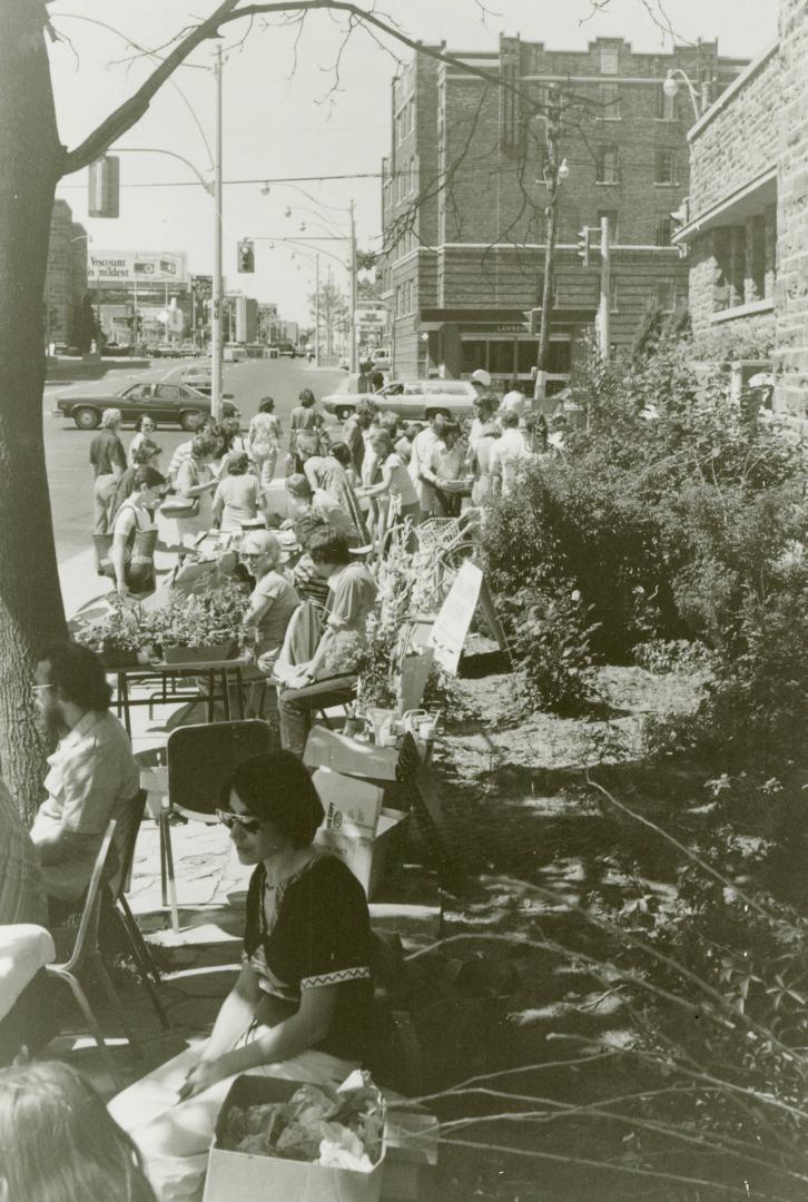 Picture of a crowd of people at tables in front of library building. 