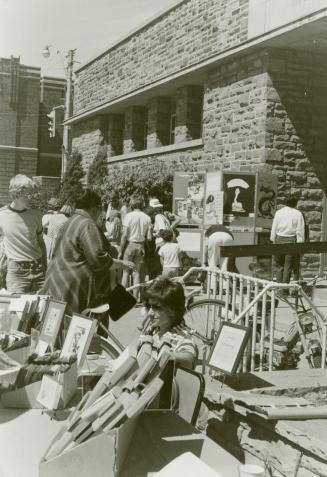 Picture of people at tables of displays outside library building. 