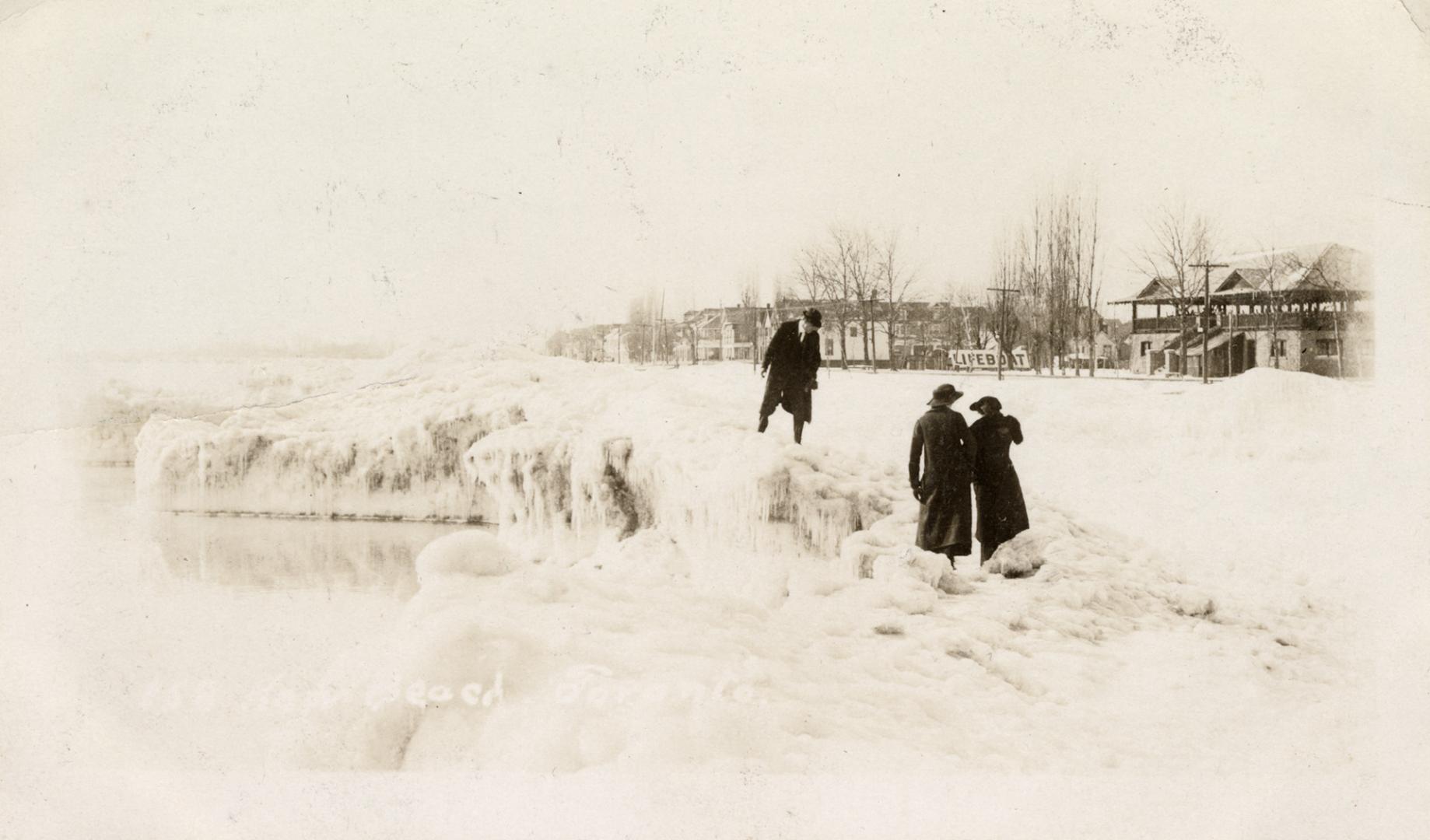 Black and white photograph of a frozen beach shoreline with people standing amidst the ice.