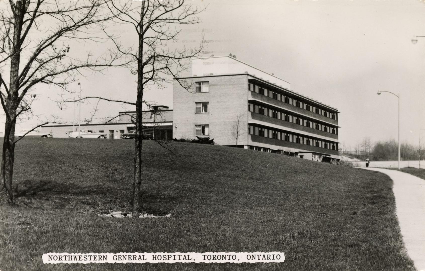 Black and white photograph of a large, L shaped, three story building.