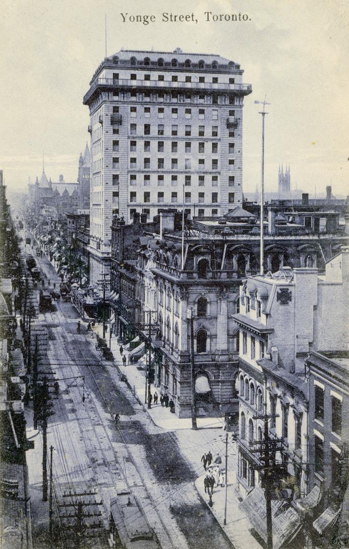 Black and white photograph of a city street with a skyscraper on the right hand side.