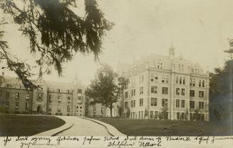 Black and white photograph of a huge collegiate gothic complex surrounded by trees.